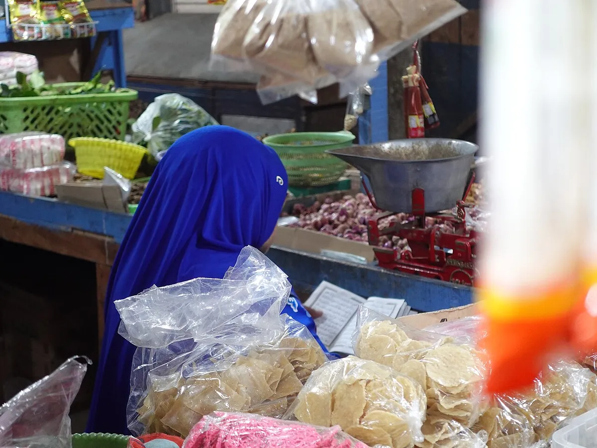 Foto contoh: seorang ibu duduk dan membaca Al-Qur'an dengan khusyuk.